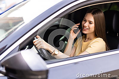 young woman driving car and talking on cell phone concentrating on the road Stock Photo