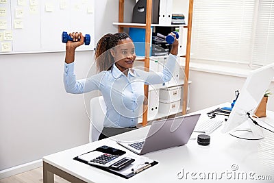 Businesswoman Exercising With Dumbbells Stock Photo