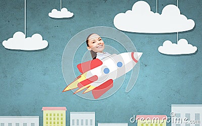 Businesswoman flying on rocket above cartoon city Stock Photo