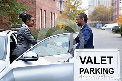 Businesswoman Giving Car Key To Male Valet Stock Photo