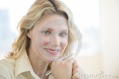 Businesswoman With Hand On Chin Smiling In Office Stock Photo