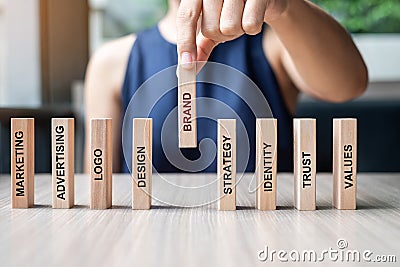 Businesswoman hand placing or pulling wooden Dominoes with BRAND text. and Marketing, Advertising, Logo, Design, Strategy, Stock Photo