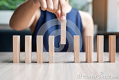 Businesswoman hand placing or pulling wooden Dominoes Stock Photo