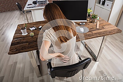 Businesswoman Having Back Pain At Workplace Stock Photo