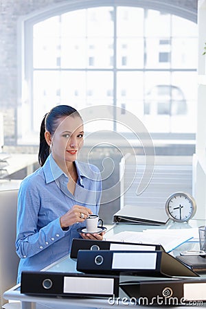 Businesswoman having coffee at desk Stock Photo