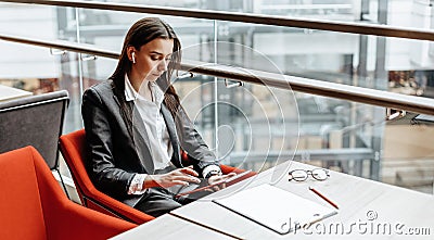Businesswoman at her workplace reads information on a tablet. A woman works with documents and searches for insights on the Stock Photo
