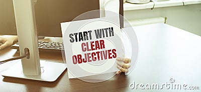 Businesswoman holding a card with text START WITH CLEAR OBJECTIVES Stock Photo