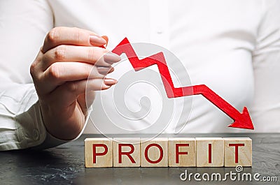 A businesswoman holds a down arrow over wooden blocks with the word Profit. The concept of reducing the company`s budget. Bad Stock Photo