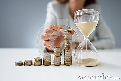 Businesswoman With Hourglass And Stack Of Coins Stock Photo