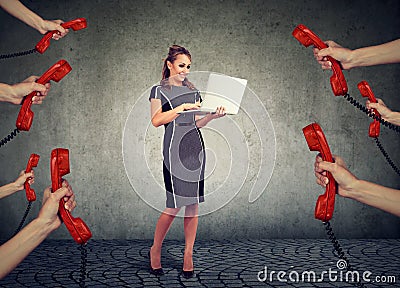 Beautiful businesswoman with laptop surrounded by many hands with phone headsets Stock Photo