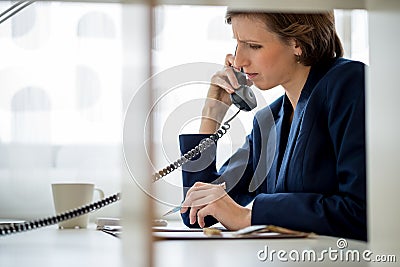 Businesswoman or manageress talking on a landline phone Stock Photo