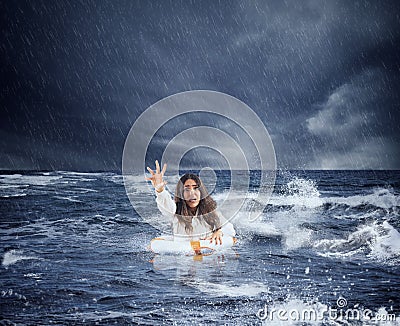 Businesswoman in the ocean with lifebelt asks help during a storm Stock Photo