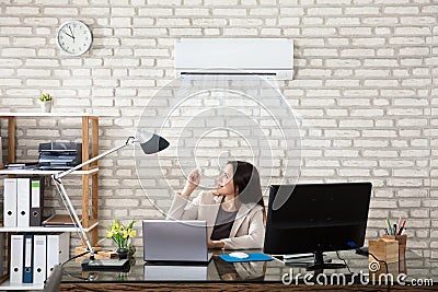 Businesswoman Operating Air Conditioner Stock Photo