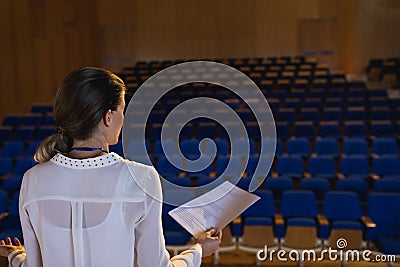 Businesswoman practicing and learning script while standing in the auditorium Stock Photo