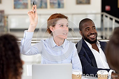 Businesswoman raising hand ask question at diverse group corporate training Stock Photo