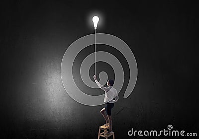 Businesswoman reaching light bulb Stock Photo