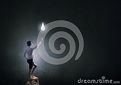 Businesswoman reaching light bulb Stock Photo