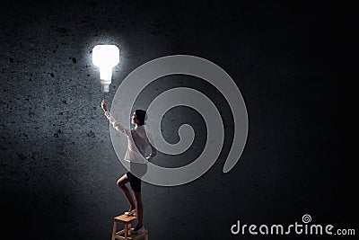 Businesswoman reaching light bulb Stock Photo