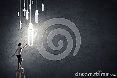 Businesswoman reaching light bulb Stock Photo