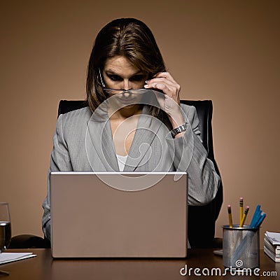 Businesswoman removing eyeglasses, working late Stock Photo