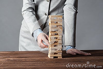 Businesswoman removing wooden block from tower Stock Photo