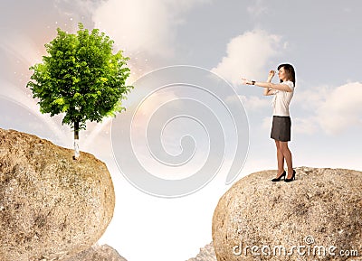 Businesswoman on rock mountain with a tree Stock Photo