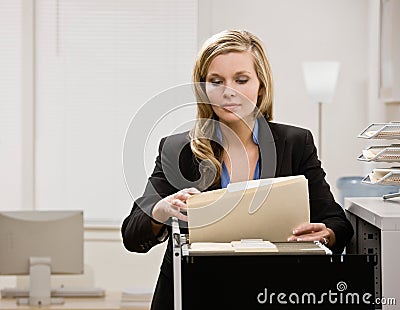 Businesswoman searches through file drawer Stock Photo