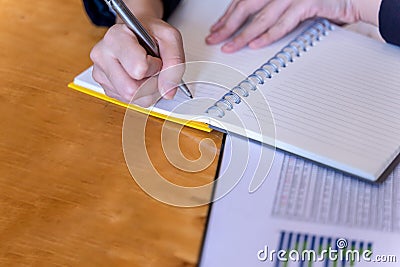 Businesswoman or Secretary hands making notes on wooden table. Writing idea on opened notebook Stock Photo