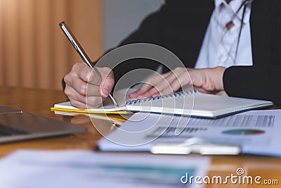 Businesswoman or Secretary holding silver pen ready to make note in opened notebook sheet. Business finances and Secretary concept Stock Photo