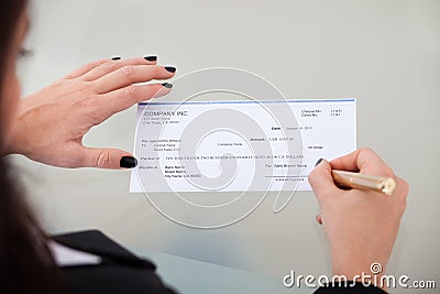 Businesswoman signing cheque Stock Photo