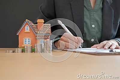 businesswoman signing mortgage loan contract with house model co Stock Photo