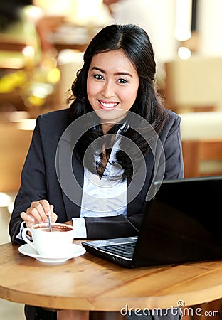Businesswoman smiling while stirring a coffee Stock Photo