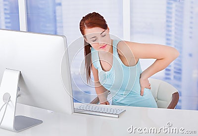 Businesswoman suffering from backache at computer desk Stock Photo