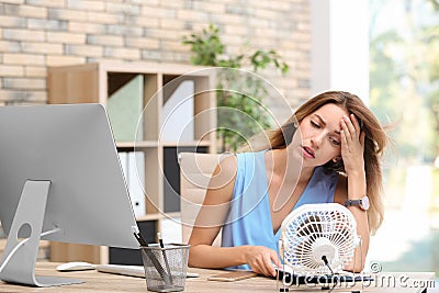 Businesswoman suffering from heat in front of small fan Stock Photo
