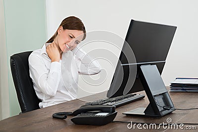 Businesswoman Suffering From Neckache At Desk Stock Photo