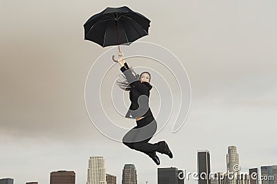 Businesswoman With An Umbrella Flying Above City Stock Photo