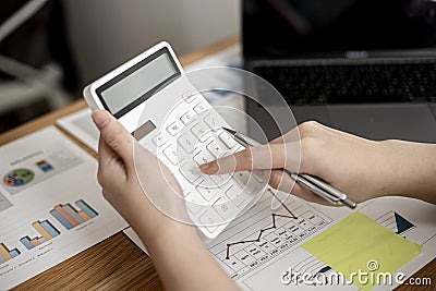 Businesswoman is using a calculator to check the numbers on a company financial document during a meeting with shareholders. Stock Photo