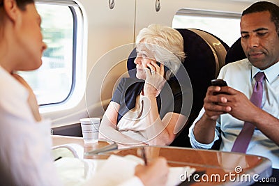 Businesswoman Using Mobile Phone On Busy Commuter Train Stock Photo