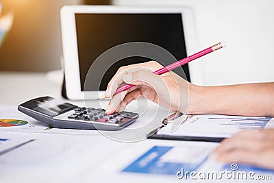 Businesswoman using tablet computer and calculator for calculating financial documents. Accounting,Finances and economy concept. Stock Photo