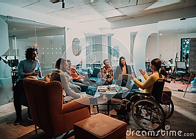 Businesswoman in wheelchair having business meeting with team at modern office. A group of young freelancers agree on Stock Photo