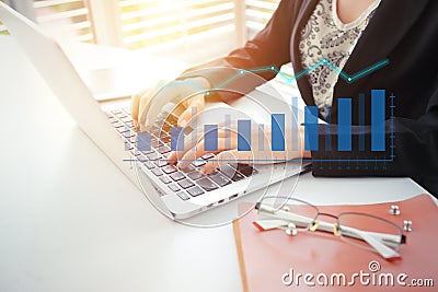 Businesswoman working on analytics and reporting company profit summary with laptop computer and glasses on desk Stock Photo