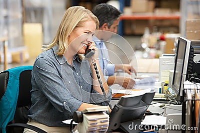 Businesswoman Working At Desk In Warehouse Stock Photo