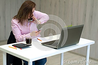 Businesswoman working at her desk in office. Woman talking on the phone and sitting in front of computer monitor Stock Photo