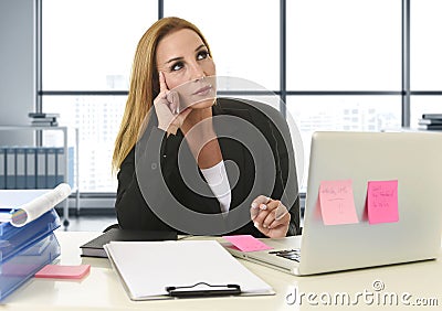 Businesswoman working at laptop computer sitting on the desk absent minded Stock Photo