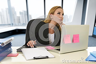 Businesswoman working at laptop computer sitting on the desk absent minded Stock Photo