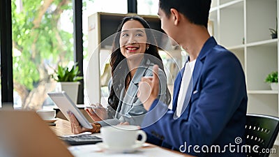 A businesswoman is working on a new project and being complimented by a male colleague Stock Photo