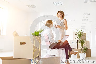 Businesswomen discussing amidst cardboard boxes at new office Stock Photo