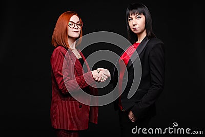 Businesswomen having a handshake.Business partners showing dislike to their business deal. Isolate on black. Stock Photo