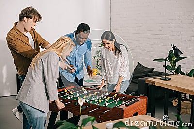 businesswomen playing table football and two male colleagues pointing Stock Photo