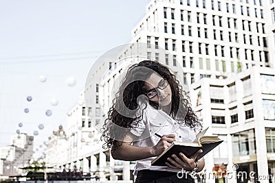 Businnes woman talking on the mobile phone with client and checks the schedule in her notebook Stock Photo